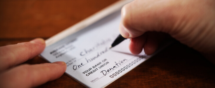 Close up view of hand writing a donation check